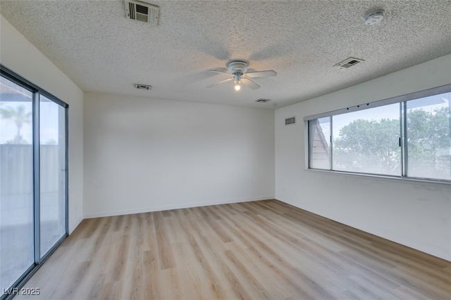 Unfurnished room featuring a smoke detector, light wood-style flooring, plenty of natural light, a ceiling fan, and a textured ceiling | Image 37