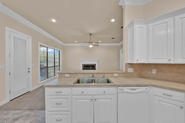 Kitchen with white dishwasher, a ceiling fan, light countertops, a peninsula, and crown molding | Image 10