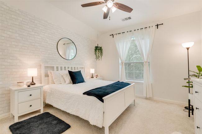 Bedroom featuring brick wall, light colored carpet, lofted ceiling, baseboards, and ceiling fan | Image 24