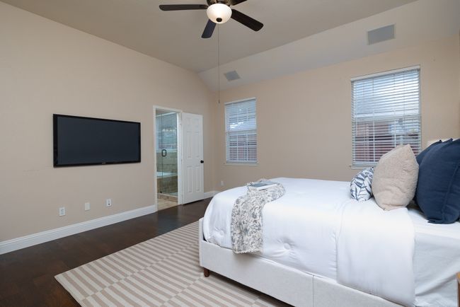 Bedroom with wood finished floors, lofted ceiling, ensuite bathroom, ceiling fan, and multiple windows | Image 17