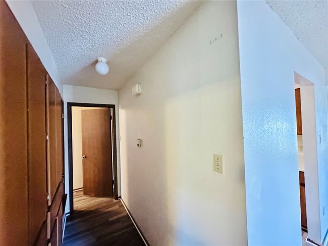 Hallway with a textured ceiling and dark wood-style floors | Image 26
