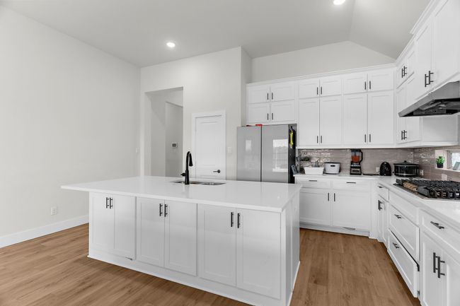 Kitchen featuring a sink, stainless steel appliances, tasteful backsplash, an island with sink, and lofted ceiling | Image 10