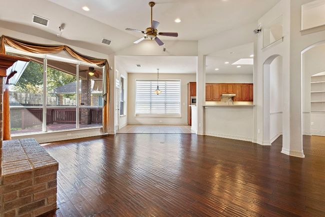 Unfurnished living room featuring hardwood / wood-style floors, visible vents, a ceiling fan, and baseboards | Image 9