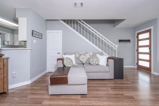Living room with stairway, visible vents, baseboards, and wood finished floors | Image 10