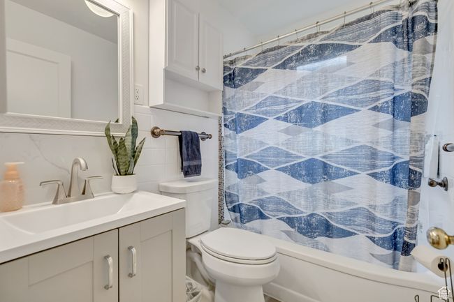 Bathroom featuring vanity, tile walls, shower / bath combo with shower curtain, and tasteful backsplash | Image 12