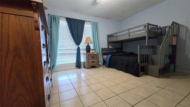 Bedroom 1 is spacious with a walk in closet and access to bathroom. The window overlooks the back parking and beauty of Galveston's tropical landscape. | Image 8