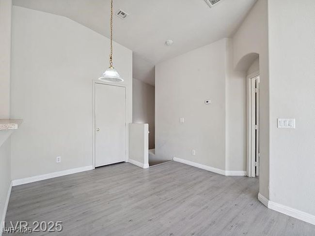Unfurnished dining area with light wood finished floors, lofted ceiling, and arched walkways | Image 15