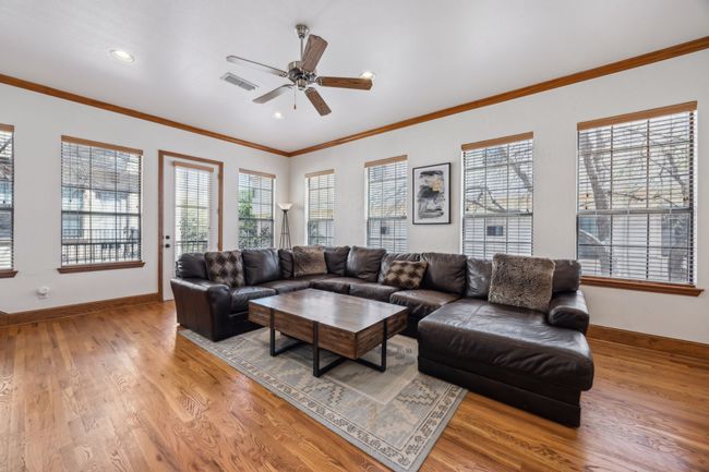 The second-floor living room is filled with natural light and features hardwood floors, a cozy fireplace, and access to a Juliet balcony. | Image 7