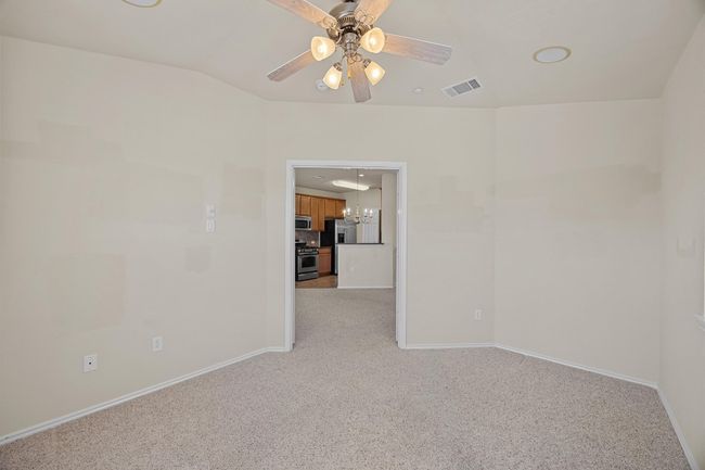 Empty room featuring light colored carpet, visible vents, baseboards, and ceiling fan with notable chandelier | Image 25