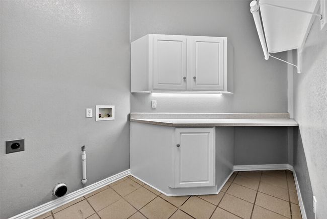 Washroom with washer hookup, electric dryer hookup, baseboards, light tile patterned flooring, and cabinet space | Image 27