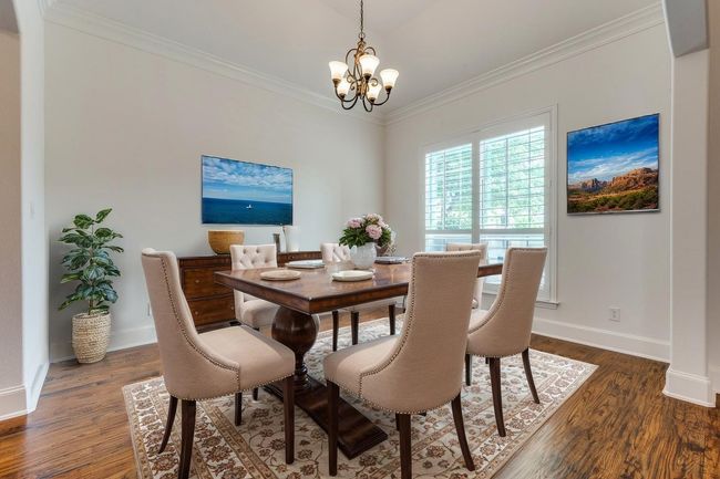 Dining space with dark wood-type flooring, baseboards, a notable chandelier, and ornamental molding | Image 6