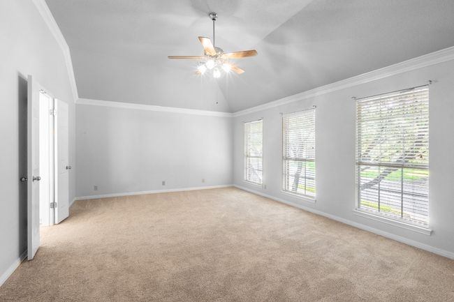 Empty room with light carpet, ceiling fan, healthy amount of natural light, lofted ceiling, and ornamental molding | Image 25