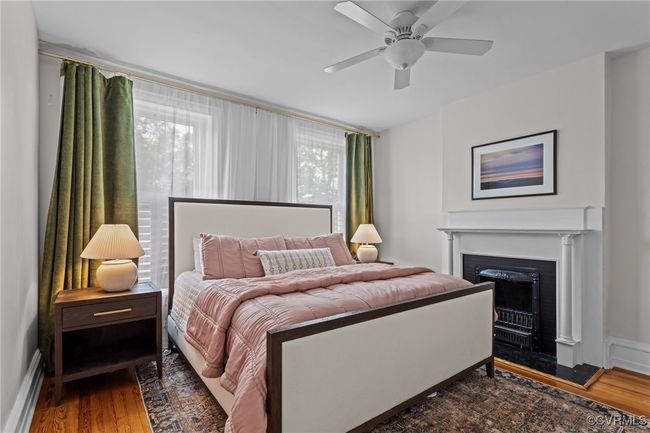 Bedroom with baseboards, a ceiling fan, wood finished floors, and a fireplace | Image 18