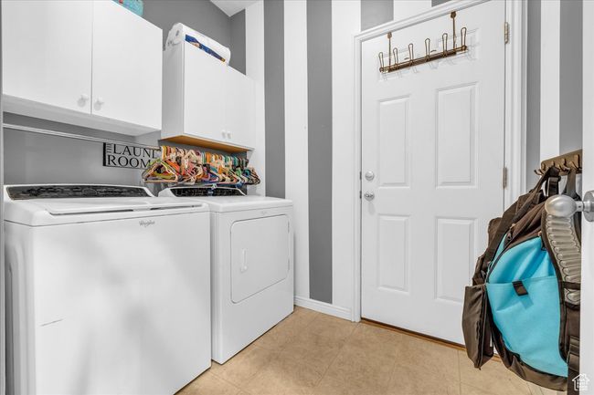 Laundry area featuring light tile patterned flooring, washer and clothes dryer, cabinet space, and baseboards | Image 22