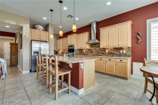 Kitchen featuring visible vents, light stone countertops, wall chimney exhaust hood, appliances with stainless steel finishes, and backsplash | Image 26