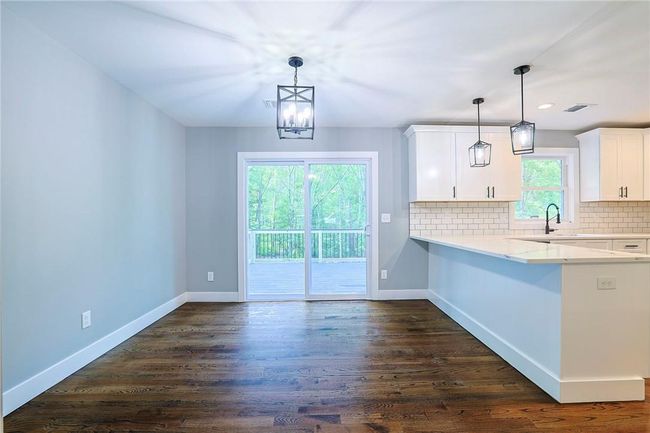 Kitchen featuring white cabinets, kitchen peninsula, dark wood-type flooring, and pendant lighting | Image 9