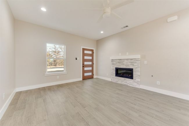 Unfurnished living room featuring light wood-type flooring, a ceiling fan, recessed lighting, and a glass covered fireplace | Image 5