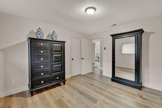 Bedroom with baseboards, a textured ceiling, visible vents, and light wood-style floors | Image 20