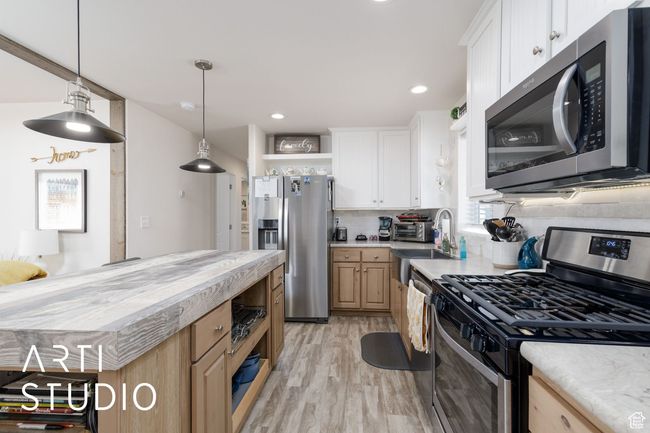 Kitchen featuring appliances with stainless steel finishes, open shelves, light countertops, tasteful backsplash, and light wood finished floors | Image 12