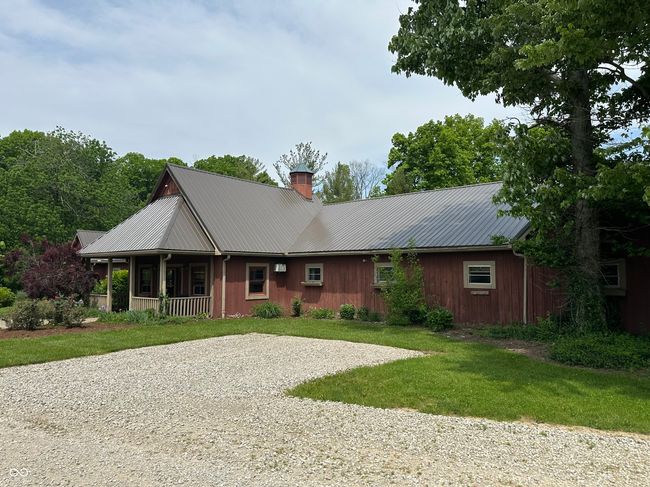 view of front facade with a chimney, a porch, a front yard, metal roof, and gravel driveway | Image 8