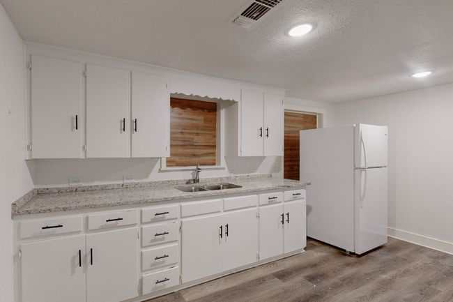 Kitchen with sink, a textured ceiling, white cabinets, and white refrigerator | Image 15
