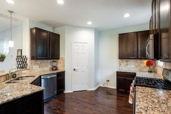 Kitchen with stainless steel appliances, dark wood-style floors, light stone countertops, dark brown cabinetry, and recessed lighting | Image 8