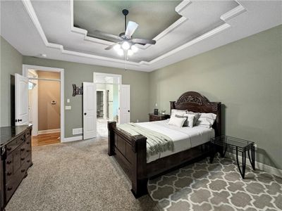 Carpeted bedroom with a textured ceiling, a tray ceiling, and ceiling fan | Image 3