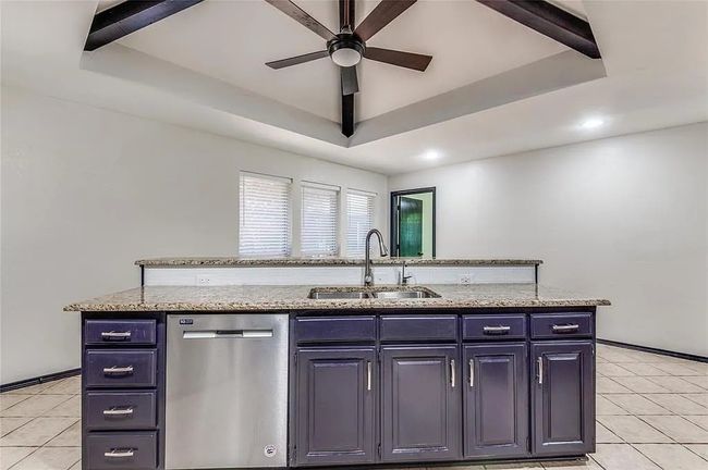 Kitchen featuring a sink, a tray ceiling, light stone counters, and dishwasher | Image 11