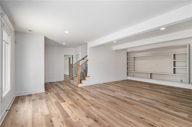 Unfurnished living room featuring light wood-style flooring, stairway, recessed lighting, and baseboards | Image 53