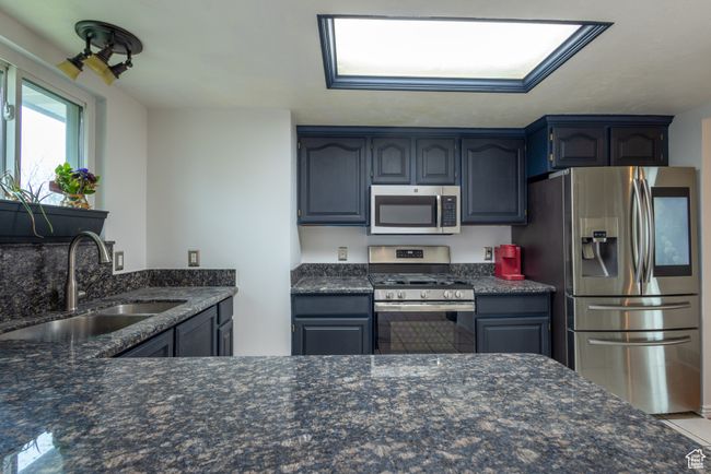 Kitchen with dark stone countertops, a sink, and appliances with stainless steel finishes | Image 6