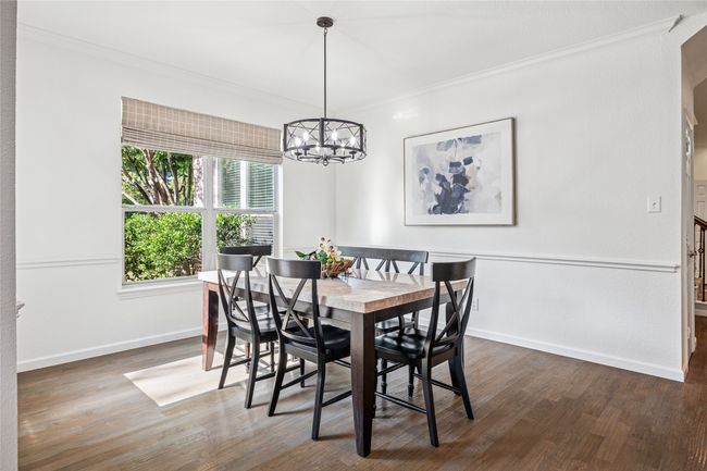 Dining space with crown molding, baseboards, a chandelier, and wood finished floors | Image 11
