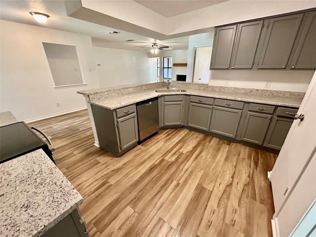 Kitchen featuring stainless steel dishwasher, a sink, light wood finished floors, a peninsula, and gray cabinets | Image 10