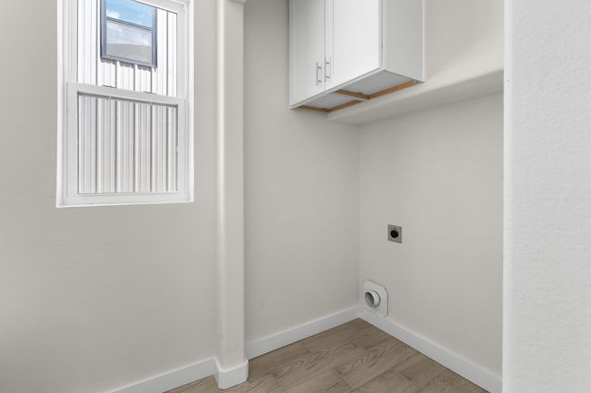 Laundry room with hookup for an electric dryer, cabinet space, and light wood-style floors | Image 11