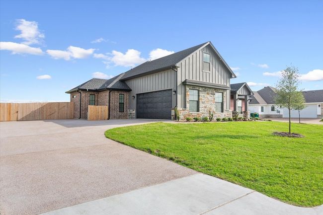View of front of home featuring driveway, board and batten siding, a garage, and stone siding | Image 40
