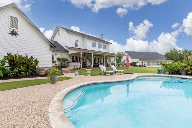 View of the pool, back of main garage, back patio, and detached workshop and greenhouse. | Image 9