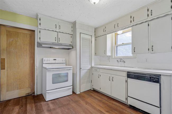 Kitchen with white appliances, under cabinet range hood, a sink, dark wood-style floors, and a textured ceiling | Image 6