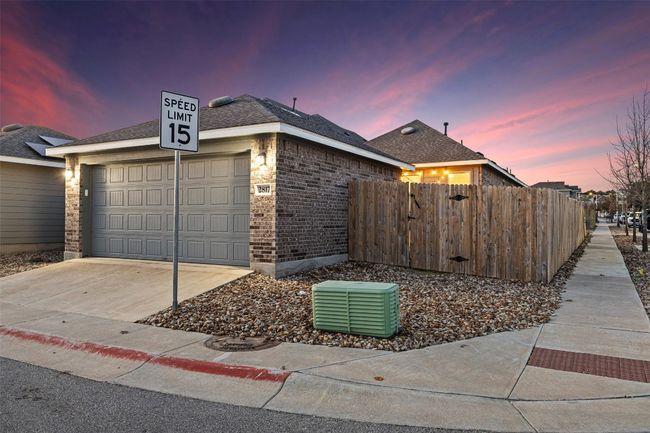 View of side of home with central AC, fence, concrete driveway, a garage, and brick siding | Image 28