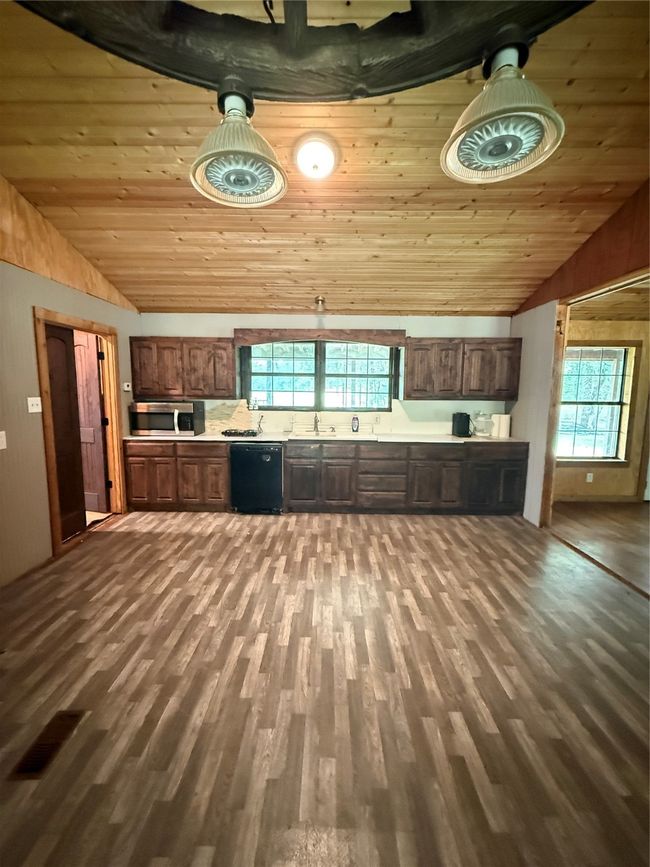 Kitchen featuring vaulted ceiling, a sink, dishwashing machine, light countertops, and healthy amount of natural light | Image 21