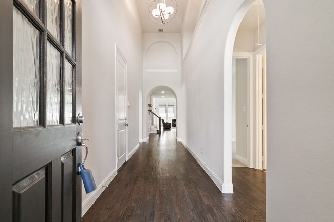 Entrance foyer with dark wood-style flooring, baseboards, a towering ceiling, arched walkways, and a notable chandelier | Image 4