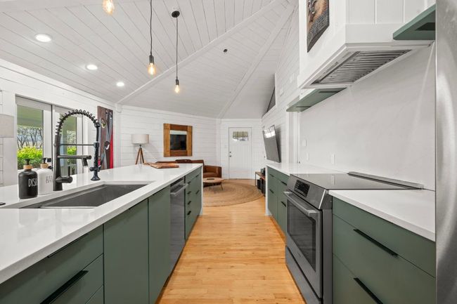 Kitchen featuring appliances with stainless steel finishes, vaulted ceiling with beams, green cabinets, and a sink | Image 12