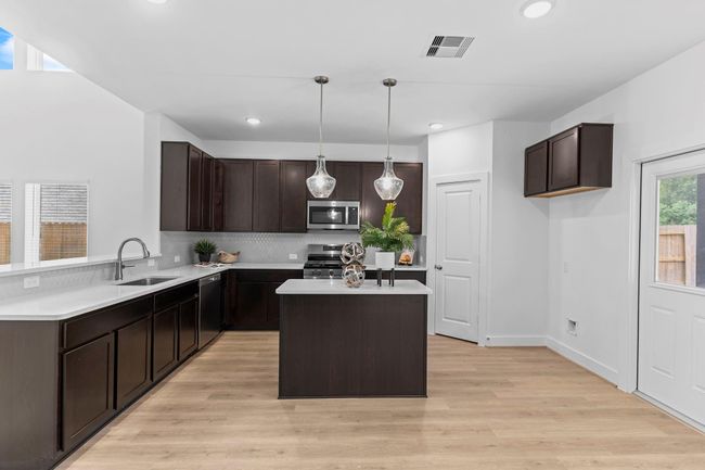 Striking kitchen design includes 42" upper cabinets, a gas range, built-in microwave, and walk-in pantry, all under recessed and pendant lighting that brings warmth and function. **Image Representative of Plan Only and May Vary as Built**. | Image 13