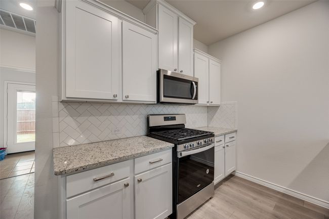 Kitchen with appliances with stainless steel finishes, light wood-style floors, tasteful backsplash, white cabinetry, and recessed lighting | Image 19