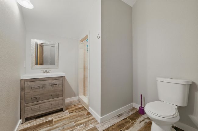 Full bath featuring vanity, toilet, wood finished floors, tiled shower, and baseboards | Image 37