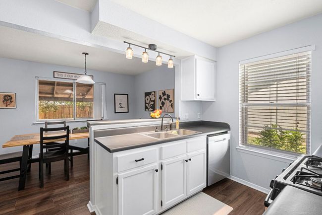 Kitchen with a sink, dishwasher, a peninsula, dark wood-type flooring, and white cabinets | Image 13