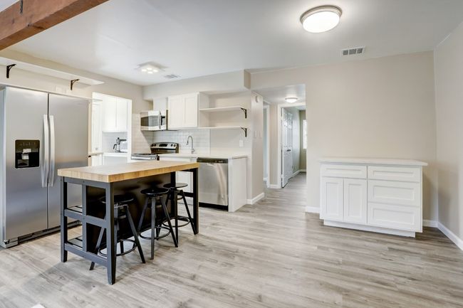 Kitchen with light wood-style floors, open shelves, visible vents, stainless steel appliances, and wooden counters | Image 4