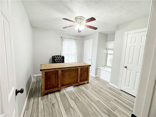 Office with light wood finished floors, plenty of natural light, a ceiling fan, and baseboards | Image 6