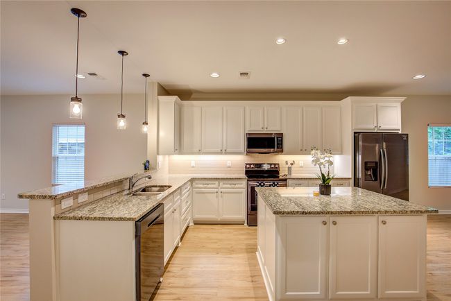 Kitchen with appliances with stainless steel finishes, light wood-style floors, tasteful backsplash, light stone counters, and recessed lighting | Image 10