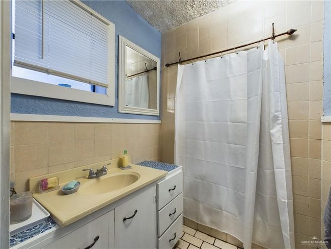 Bathroom with tile flooring, tasteful backsplash, vanity with extensive cabinet space, and tile walls | Image 10