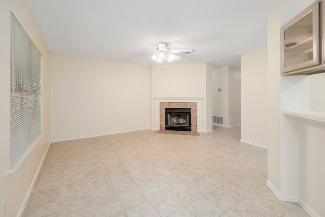 Unfurnished living room featuring a ceiling fan, a tiled fireplace, and baseboards | Image 6