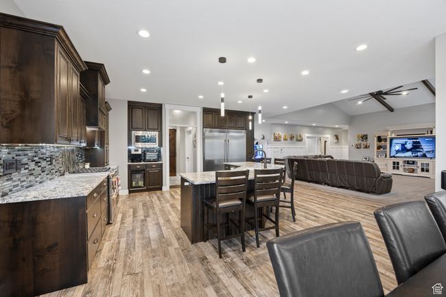 Kitchen with built in appliances, open floor plan, dark brown cabinets, a kitchen breakfast bar, and recessed lighting | Image 14